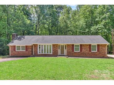 Charming brick ranch home with a lush green lawn and mature trees surrounding the property at 182 Freedom Mill Rd, Gastonia, NC 28052