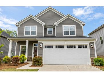 Charming two-story home featuring gray siding, white trim, manicured landscaping, and an attached two-car garage at 1933 Tin Roof Ln, Monroe, NC 28112