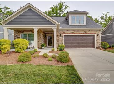 Charming home showcasing stone accents, a covered porch, and a well-manicured front yard at 2306 Wesley Landing Rd, Waxhaw, NC 28173