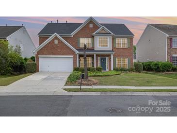 Charming two-story red brick home with attached garage and well-manicured front lawn at 5803 Lindley Crescent Dr, Indian Trail, NC 28079