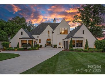Striking white brick home with dark trim, manicured lawn, and lush landscaping at sunset at 7861 Live Oaks Dr, Denver, NC 28037
