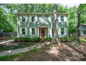 Charming two-story home with sage green siding, white shutters and a red front door surrounded by lush landscaping at 8936 Rittenhouse Cir, Charlotte, NC 28270