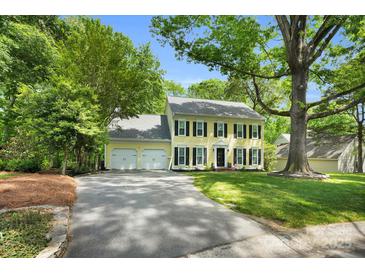 Traditional two-story home with yellow siding, black shutters, and a well-manicured front lawn at 9809 Hanover Hollow Dr, Charlotte, NC 28210