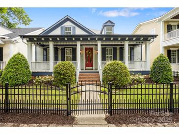 Charming home with a black fence, landscaped yard, and a covered porch with white columns and a red front door at 16919 Hedgerow Park Rd, Charlotte, NC 28277