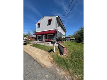 Charming two-story home with red awnings, a cozy porch swing, and well-maintained lawn at 310 4Th W St, Newton, NC 28658