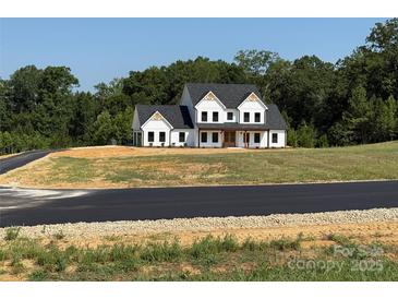 Beautiful two-story white farmhouse with a dark roof and lush greenery in the background at 4034 Daugherty Rd, China Grove, NC 28023