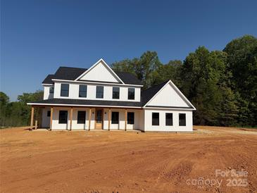 Newly constructed two-story home with black trim, covered porch and wooded backdrop at 4040 Daugherty Rd, China Grove, NC 28023