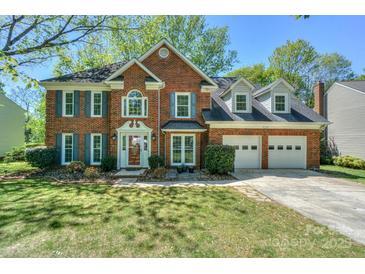 Charming two-story red brick home featuring an attached two-car garage and beautifully manicured front yard at 8709 Stratton Farm Rd, Huntersville, NC 28078