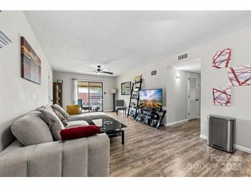 Comfortable living room featuring a neutral sectional sofa and wood-look flooring, brightened by natural light at 123 Carriage House Dr, Kannapolis, NC 28081