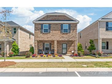 Charming two-story brick home featuring a covered front porch and manicured landscaping at 1316 Colgher St, Mint Hill, NC 28227