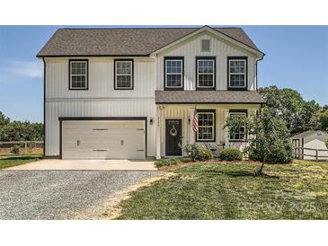 Charming two-story home featuring a white exterior, black trim, an attached garage, and a well-maintained lawn at 2206 Mills Harris Rd, Wingate, NC 28174