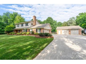 Charming two-story home featuring an attached garage, a detached three-car garage, and a well-manicured front lawn at 4145 Wrangler Sw Dr, Concord, NC 28027
