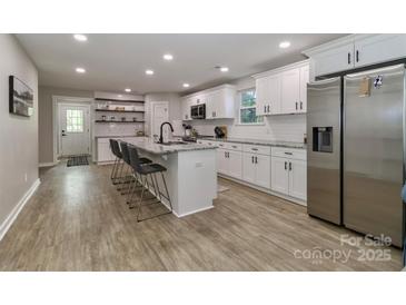 Bright kitchen with white cabinetry, stainless appliances, and a large center island with seating at 703 S Main St, Landis, NC 28088