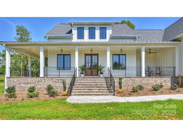 Inviting two-story white home with a brick foundation, grand staircase, and manicured front yard at 7768 Lynwood Ln, Sherrills Ford, NC 28673