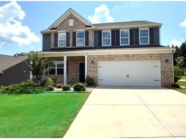 Two-story brick home featuring a two-car garage, manicured lawn and a welcoming front porch at 8901 Powder Works Dr, Huntersville, NC 28078