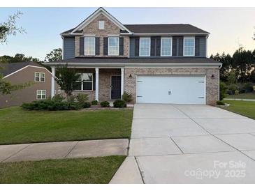 Beautiful two-story home with brick and siding, a well-manicured lawn, and an attached two-car garage at 8901 Powder Works Dr, Huntersville, NC 28078
