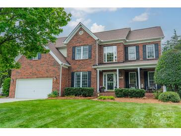 Charming brick home featuring a well-manicured lawn, a two-car garage, and classic black shutters at 8902 Whittingham Dr, Waxhaw, NC 28173