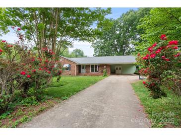Charming brick home featuring a long driveway, lush landscaping and beautiful flowers framing the entrance at 8903 Larchmont Cir, Charlotte, NC 28214