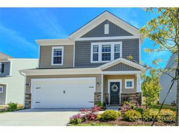 Charming two-story home showcasing a well-maintained front yard with a two car garage and stone accents at 15813 Capps Rd, Charlotte, NC 28278