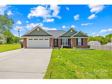 Charming brick home featuring a two-car garage, manicured lawn, and a welcoming front porch area at 201 Churchill Dr, Kings Mountain, NC 28086