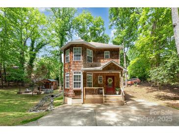 Charming two-story home featuring wood siding, a cozy front porch, and mature trees on a sunny day at 3004 Point Clear Dr, Tega Cay, SC 29708