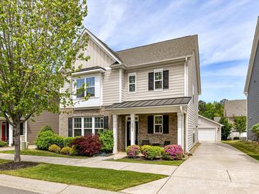 Charming two-story home featuring beautiful landscaping, a covered front porch, and a detached garage at 6312 Kennard Dr, Charlotte, NC 28216