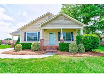 Charming single-Gathering home featuring a covered porch, a well-manicured lawn, and beautiful landscaping at 704 E Catawba St, Belmont, NC 28012