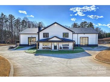 Stunning modern farmhouse with black trim, glass doors, covered porch, and manicured lawn on a sunny day at 1525 Shinnville Rd, Cleveland, NC 27013