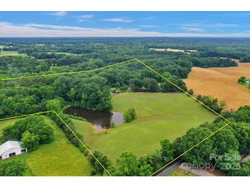 Expansive property featuring a private pond, surrounded by lush greenery and bordered by mature trees at 1607 Old Lawyers Rd, Marshville, NC 28103