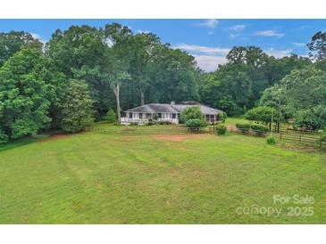Sprawling ranch home on a large lot surrounded by mature trees and a wooden fence for added charm at 1607 Old Lawyers Rd, Marshville, NC 28103
