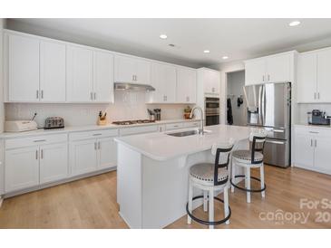 Bright, modern kitchen with white cabinets, stainless steel appliances, and a breakfast bar at 190 Tetcott St, Mooresville, NC 28115