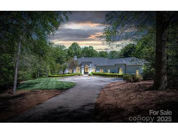 Stately home features a circular driveway and mature landscaping, creating a welcoming and private setting at 7912 Baltusrol Ln, Charlotte, NC 28210