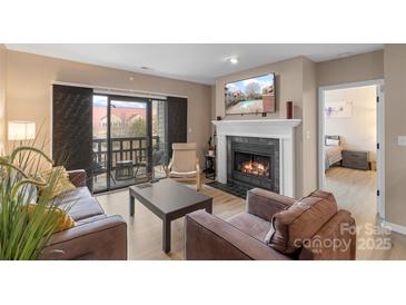 Cozy living room featuring a fireplace and sliding glass doors to a balcony with seating at 9029 J M Keynes Dr # 63, Charlotte, NC 28262