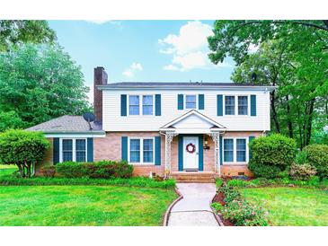Charming two-story home featuring a brick facade, white siding, green shutters, and a neatly landscaped front yard at 1287 Queensgate St, Gastonia, NC 28054