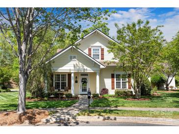 Charming two-story home with a well-manicured lawn, walkway, mature trees, and cozy front porch at 13216 Old Compton Ct, Pineville, NC 28134
