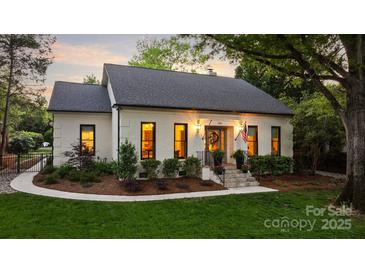 Charming white brick home with landscaped yard, stone steps, black trim windows, and a welcoming entrance at 3300 Sharon Rd, Charlotte, NC 28211