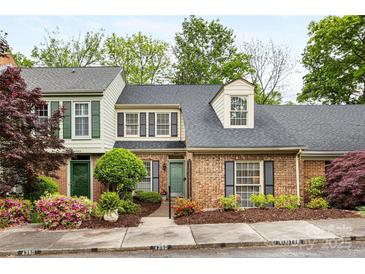 Charming brick townhome featuring a well-maintained front yard with colorful flowers and mature trees at 4360 Woodglen Ln, Charlotte, NC 28226