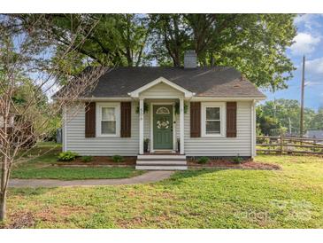 Charming cottage-style home with white siding, brown shutters, and a landscaped front yard at 506 Englewood Ne St, Concord, NC 28025