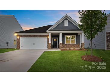 Charming single-Gathering home with a two-car garage, stone accents, manicured lawn, and welcoming front porch at 1335 Secrest Commons Dr, Monroe, NC 28112