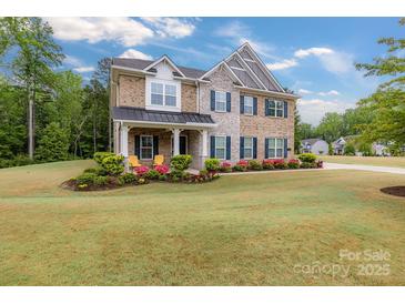 Charming two-story home with brick and stone exterior, landscaped yard and covered front porch with chairs at 4008 Pinot Way, Fort Mill, SC 29707