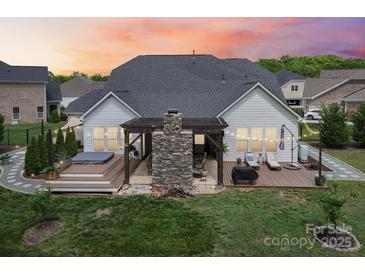 A lovely backyard with a stone fireplace, wooden pergola, hot tub, and deck provides a tranquil outdoor space at 500 Chicory Cir, Matthews, NC 28104