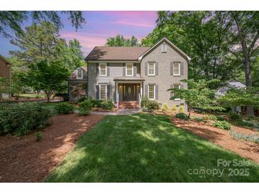 Traditional home boasts manicured lawn, mature trees, neutral paint, shutters, and covered entryway at 5206 Morrowick Rd, Charlotte, NC 28226