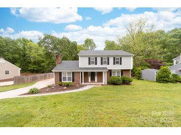 Charming two-story home with brick and vinyl siding, a well-manicured lawn, and mature trees at 616 Silversmith Ln, Charlotte, NC 28270