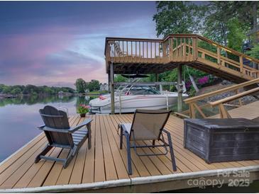 A waterfront dock area features a boat lift, seating, and picturesque lake views at sunset at 1114 Palmyra Dr, Tega Cay, SC 29708