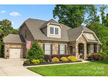 Charming home showcasing manicured lawn, stone accents, an American flag, and inviting curb appeal at 11424 Brangus Ln, Mint Hill, NC 28227