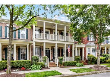 Charming brick townhouse with double porches, lush landscaping, and a welcoming American flag at 172 Harper Lee St, Davidson, NC 28036