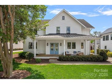 Charming white home featuring a welcoming front porch with a swing and vibrant blue double doors at 309 Catawba Ave, Davidson, NC 28036