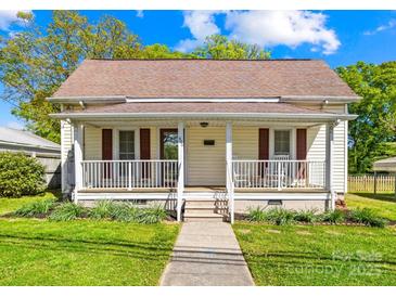 Charming home featuring a cozy front porch, well-manicured lawn, and beautiful landscaping at 406 S Gaston St, Dallas, NC 28034
