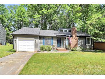Charming single-story home with gray siding, brick chimney, mature trees, and a well-manicured front lawn at 6712 Santa Maria Ln, Charlotte, NC 28227