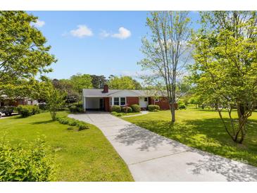 Charming red brick home featuring a covered carport, landscaped yard, and a long private driveway at 7209 Marley Cir, Charlotte, NC 28214